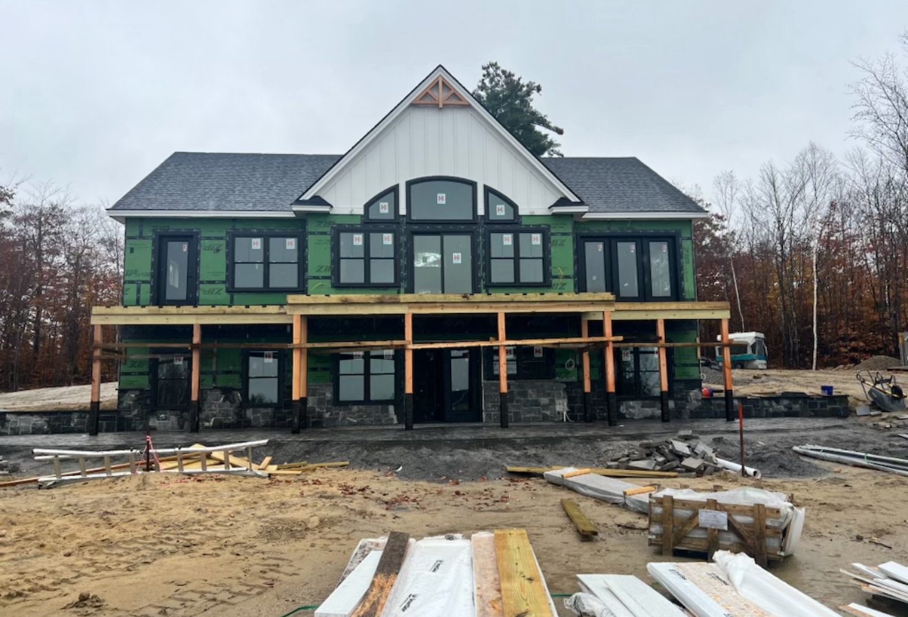 Large custom home under construction with exterior framing and weather barrier