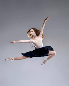 A teenage dancer lacing her pointe shoe ribbons