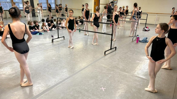 Close-up of a young dancer practicing at the ballet barre