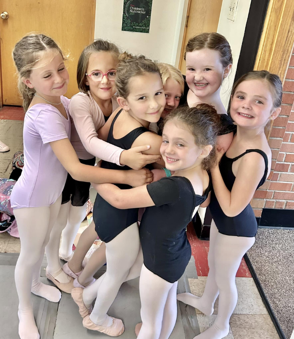Two young dancers greeting each other with a hug at the studio entrance