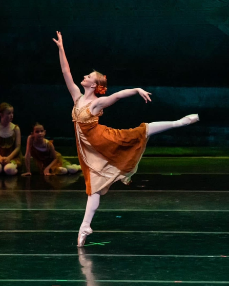 A teenage dancer lacing her pointe shoe ribbons