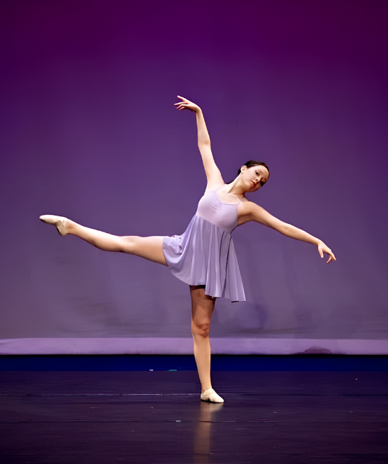 A joyful young dancer reaching upward in a sunlit studio