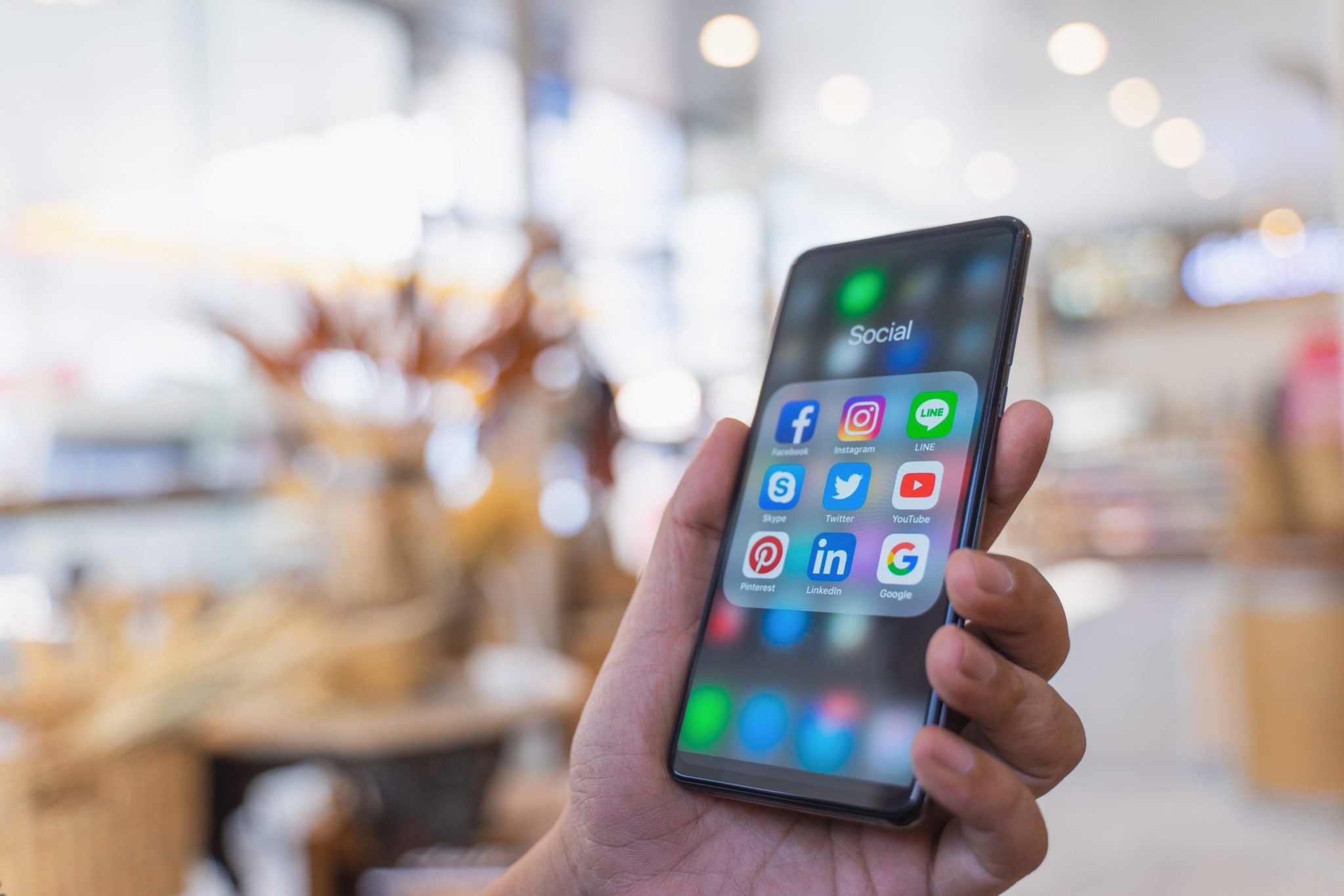 Hand holding phone with social icons