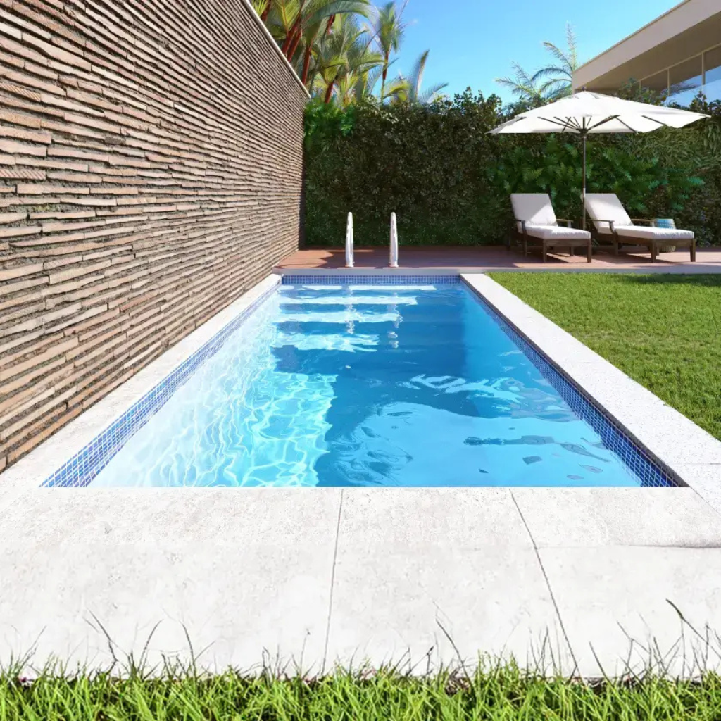 Completed rectangular fiberglass pool beside a textured privacy wall