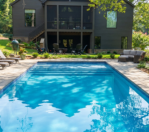 Finished rectangular fiberglass pool surrounded by mature landscaping