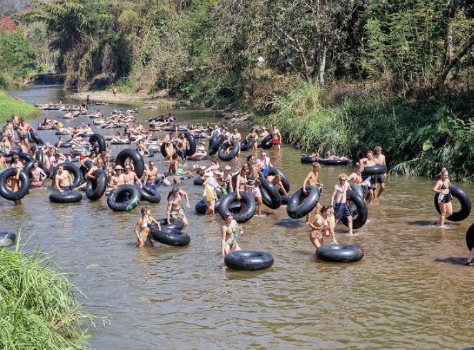 Crowds of travelers tubing down a shallow river