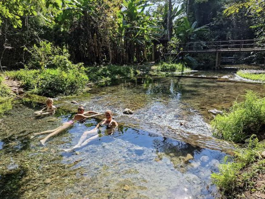 Friends relaxing in a clear jungle creek