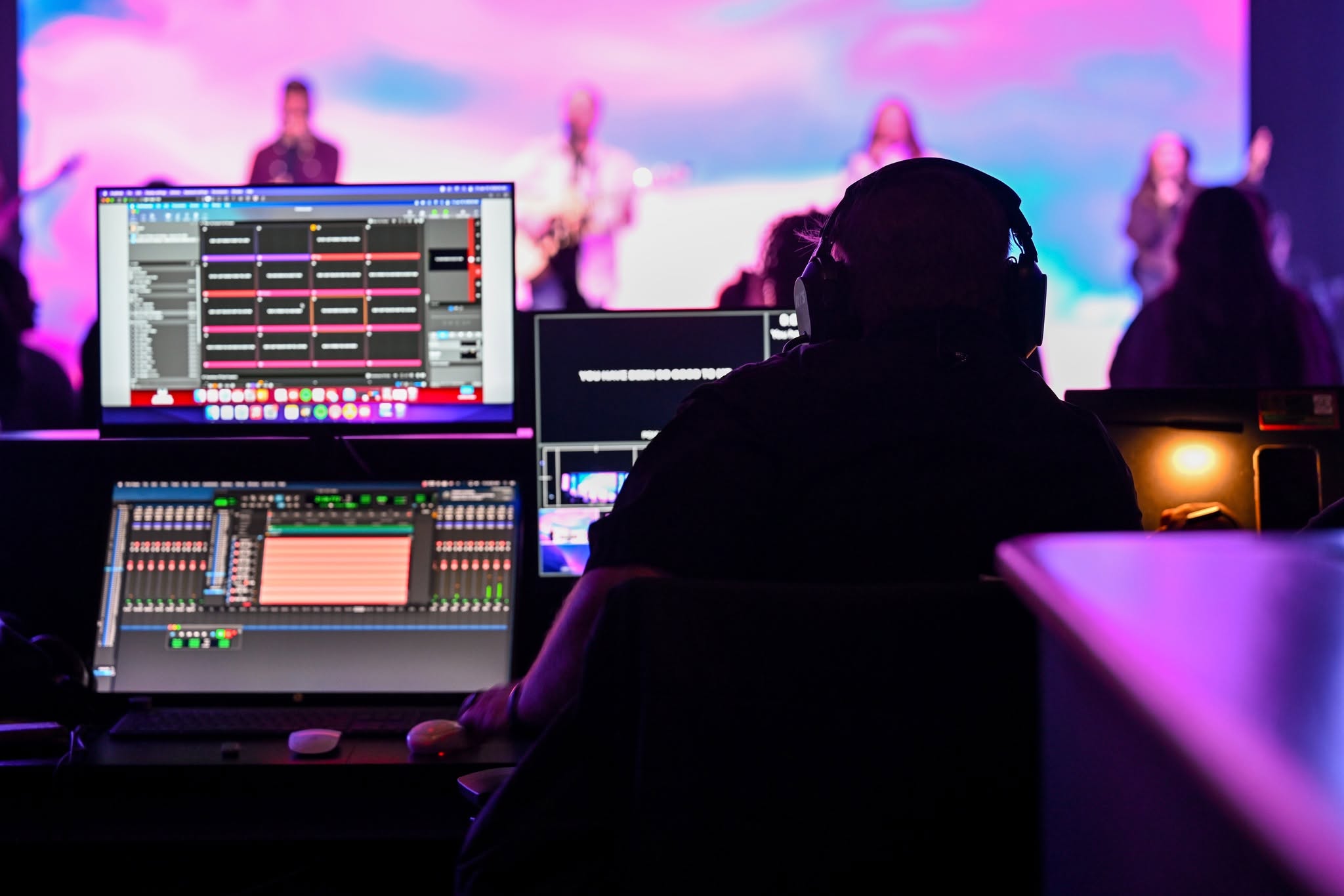 A smiling church audio engineer serving from a mixing console