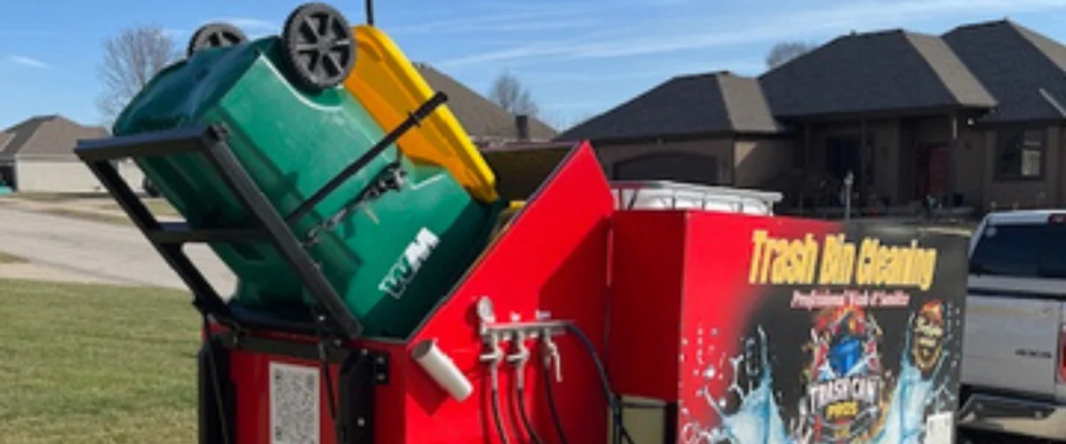 Side view of a red and black trailer for 'Trash Bin Cleaning' with 'Professional Wash & Sanitize' text, a 'Trash Can Pros LLC' logo, and 'Firefighter owned' seal.