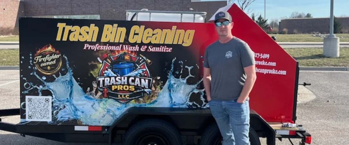 A man in a cap and sunglasses stands next to a "Trash Bin Cleaning" trailer with a firefighter-owned logo. A man in a cap and sunglasses stands next to a "Trash Bin Cleaning" trailer with a firefighter-owned logo.
