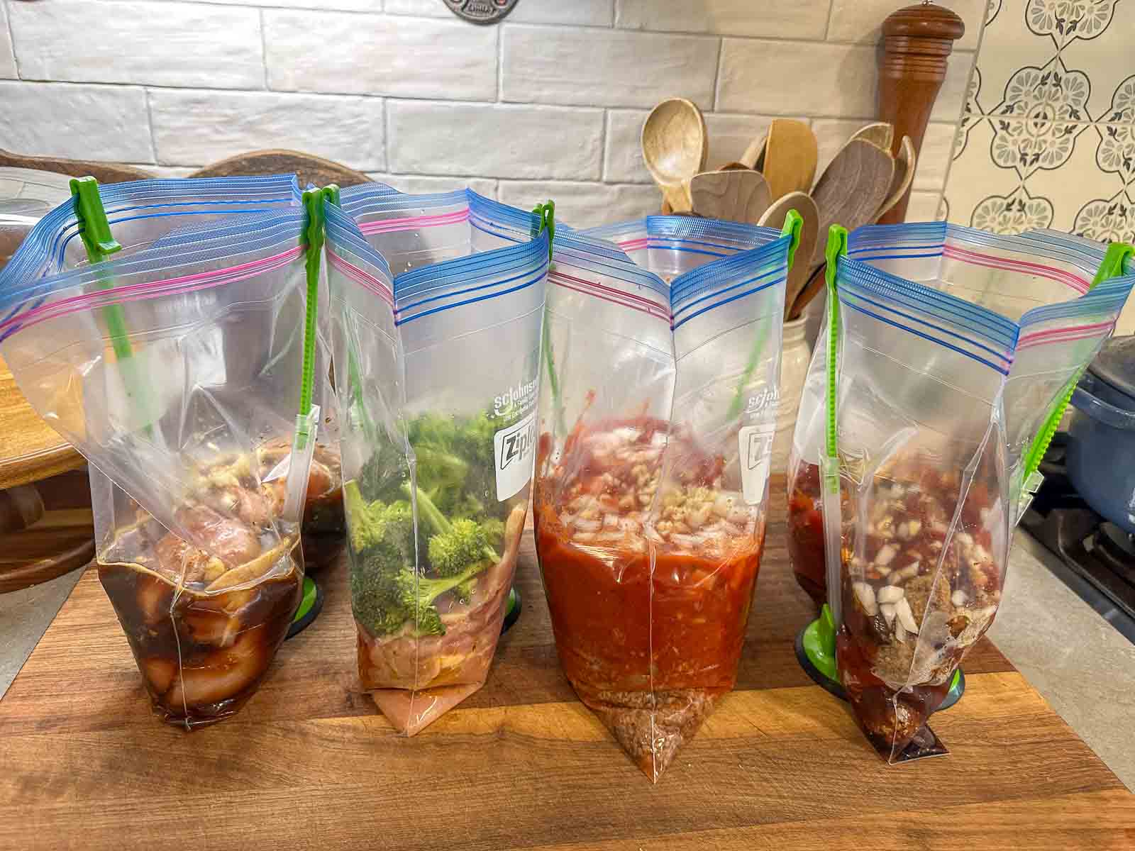 Zip-top bags filled with prepped dinner ingredients, including chicken, broccoli, sauces, and vegetables. Informative, product-related.