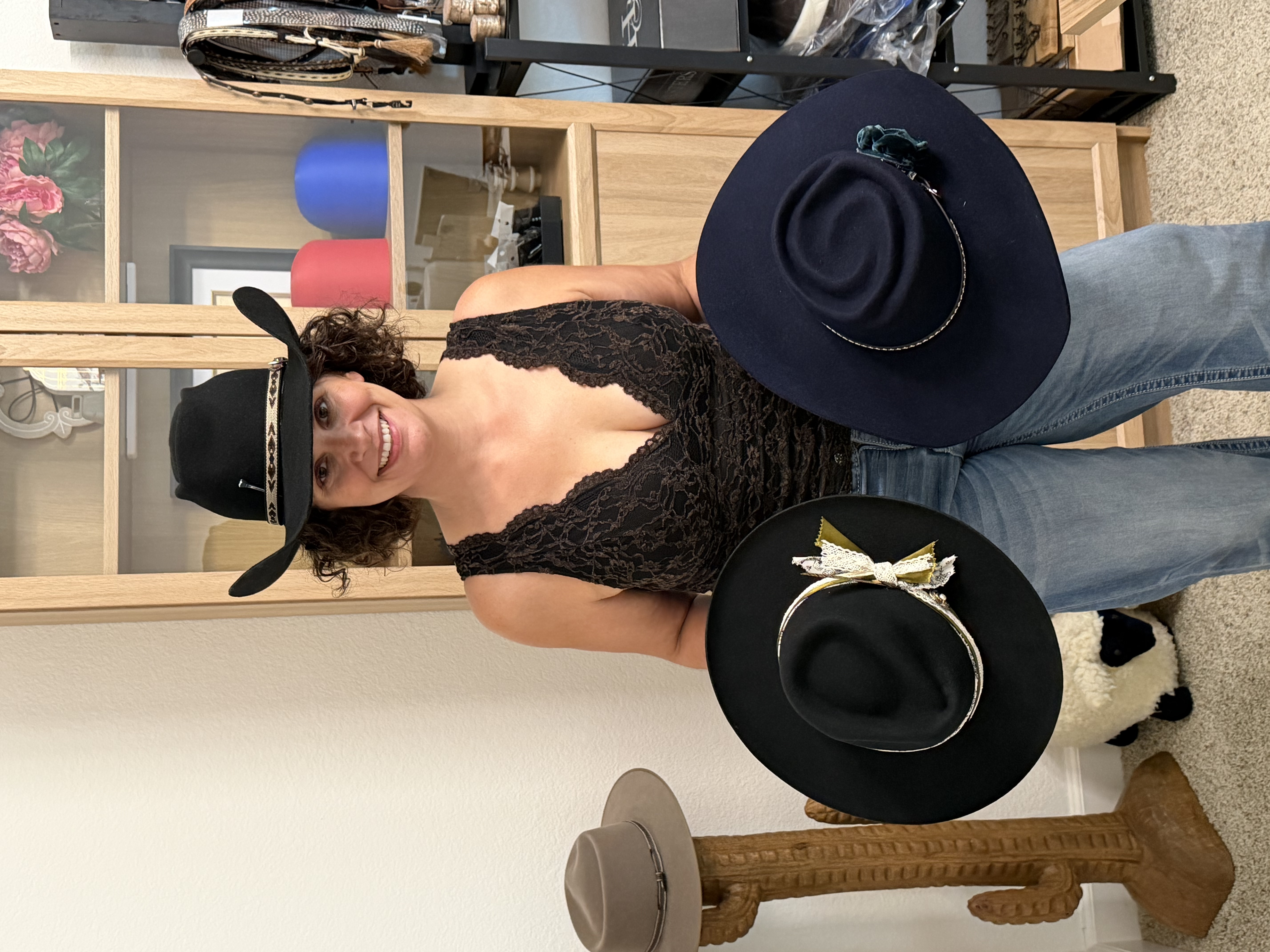 Tina holding two finished western hats in the Highland Brims studio
