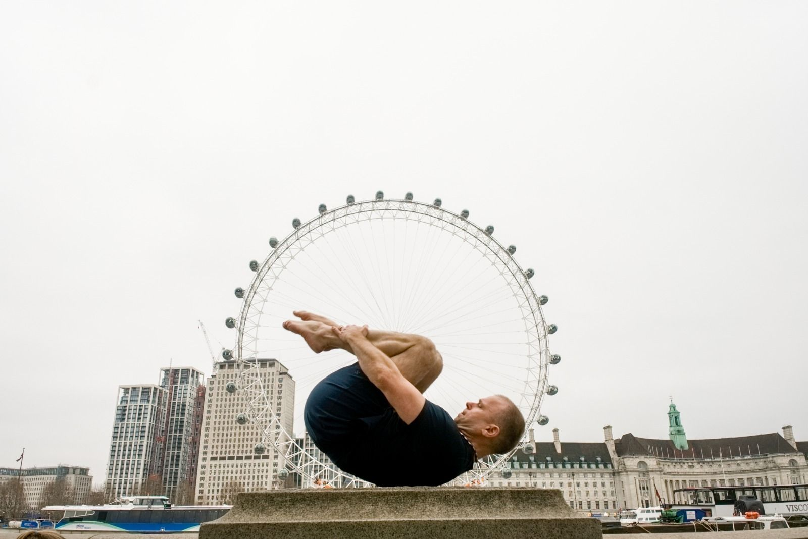Joakim performing a Pilates move in front of the London Eye