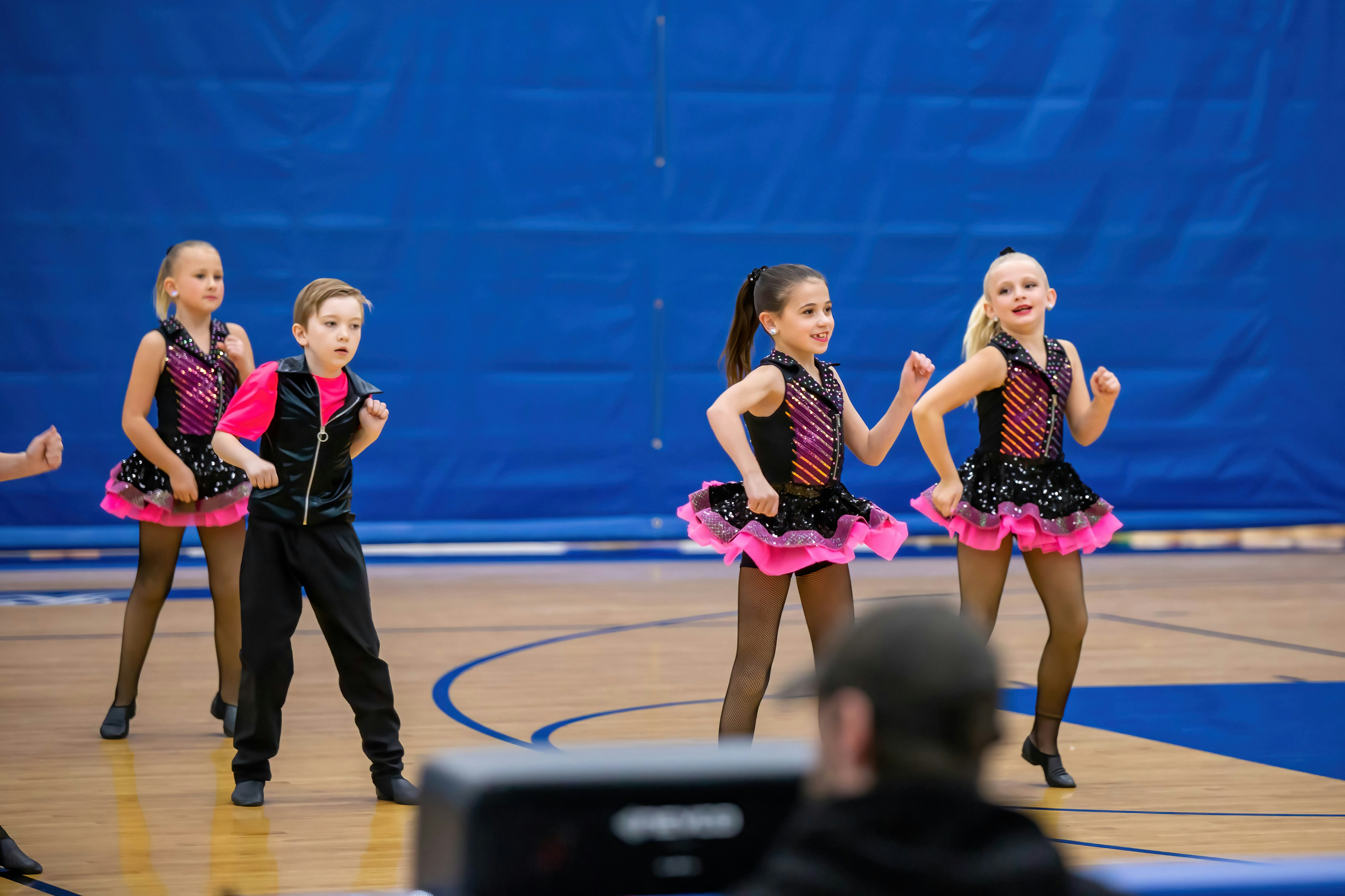 Junior ballroom dancers performing a choreographed routine at a youth dance event.