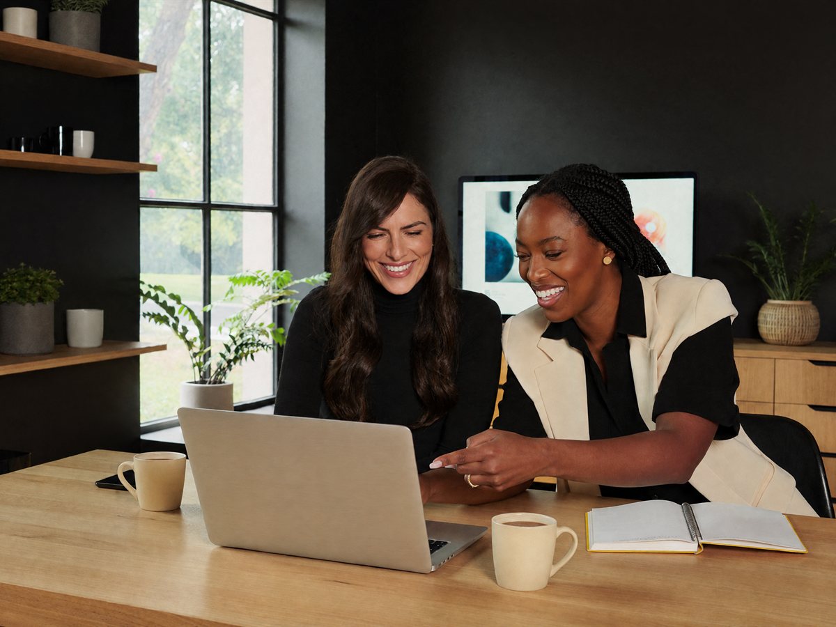 A real estate agent and her assistant reviewing a laptop together