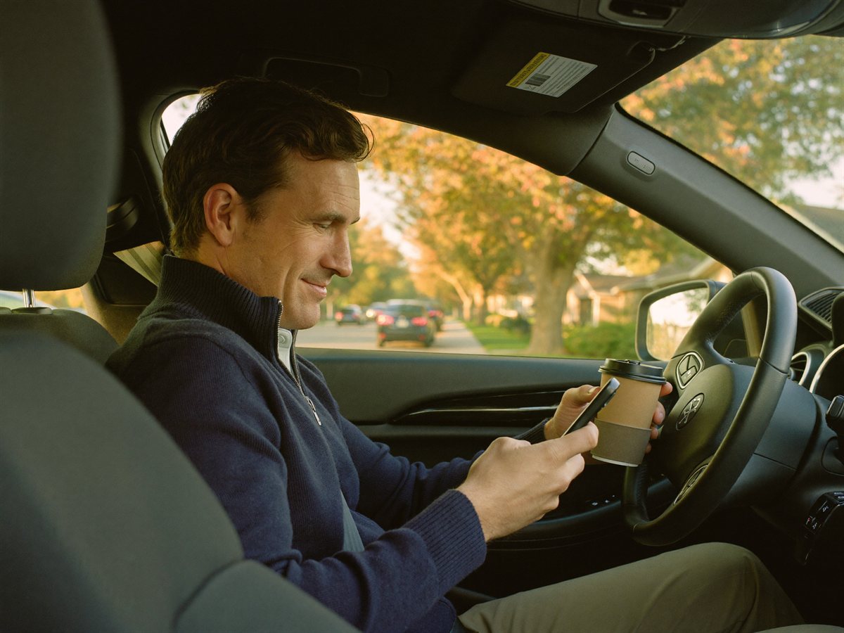 A solo agent reading his phone in his car before a showing