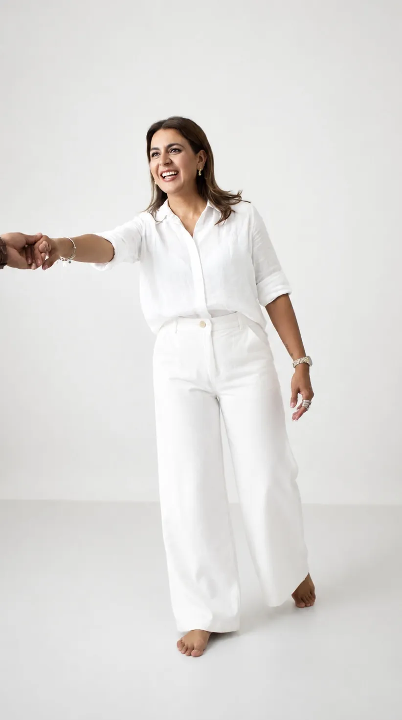 Alma Sández vestida de blanco, sonriendo y extendiendo la mano