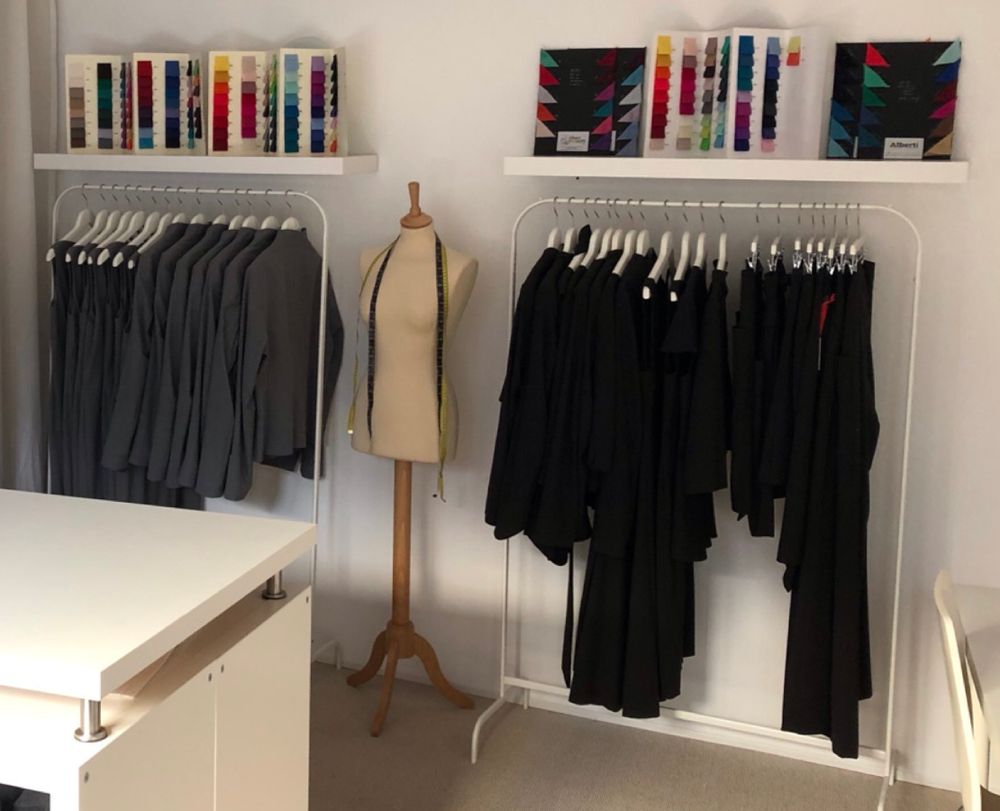 The bright ROQUA showroom: colour cards on shelves, rails of tailored pieces and a dress form with a tape measure