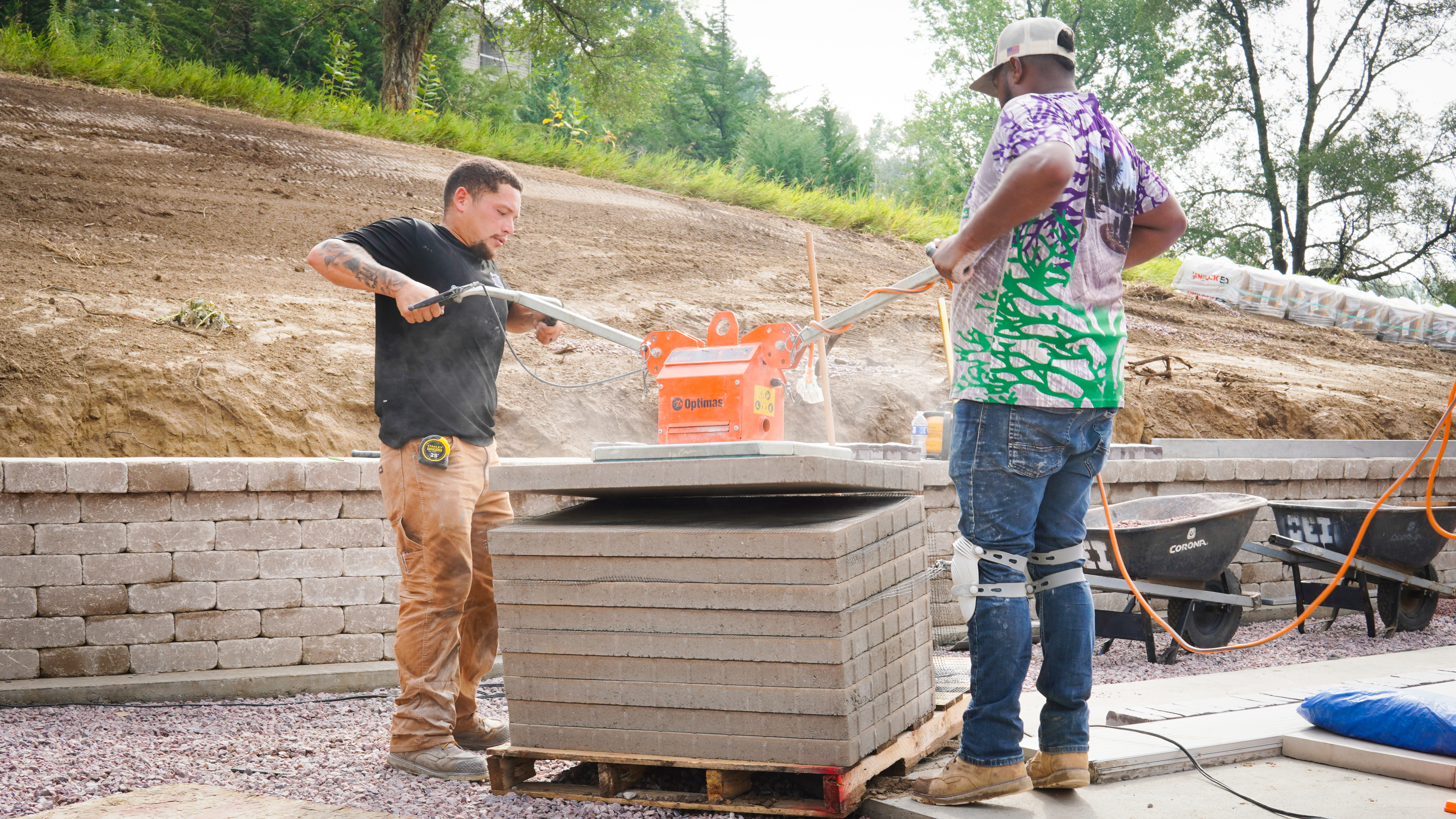 Two crew members laying block with a paver machine