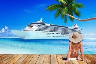 Woman sitting a beach overlooking a cruise ship in the ocean in the background
