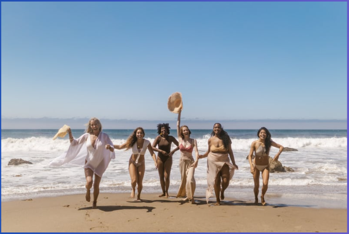 Group of women on the beach laughing and smiling. Various ages and races. 