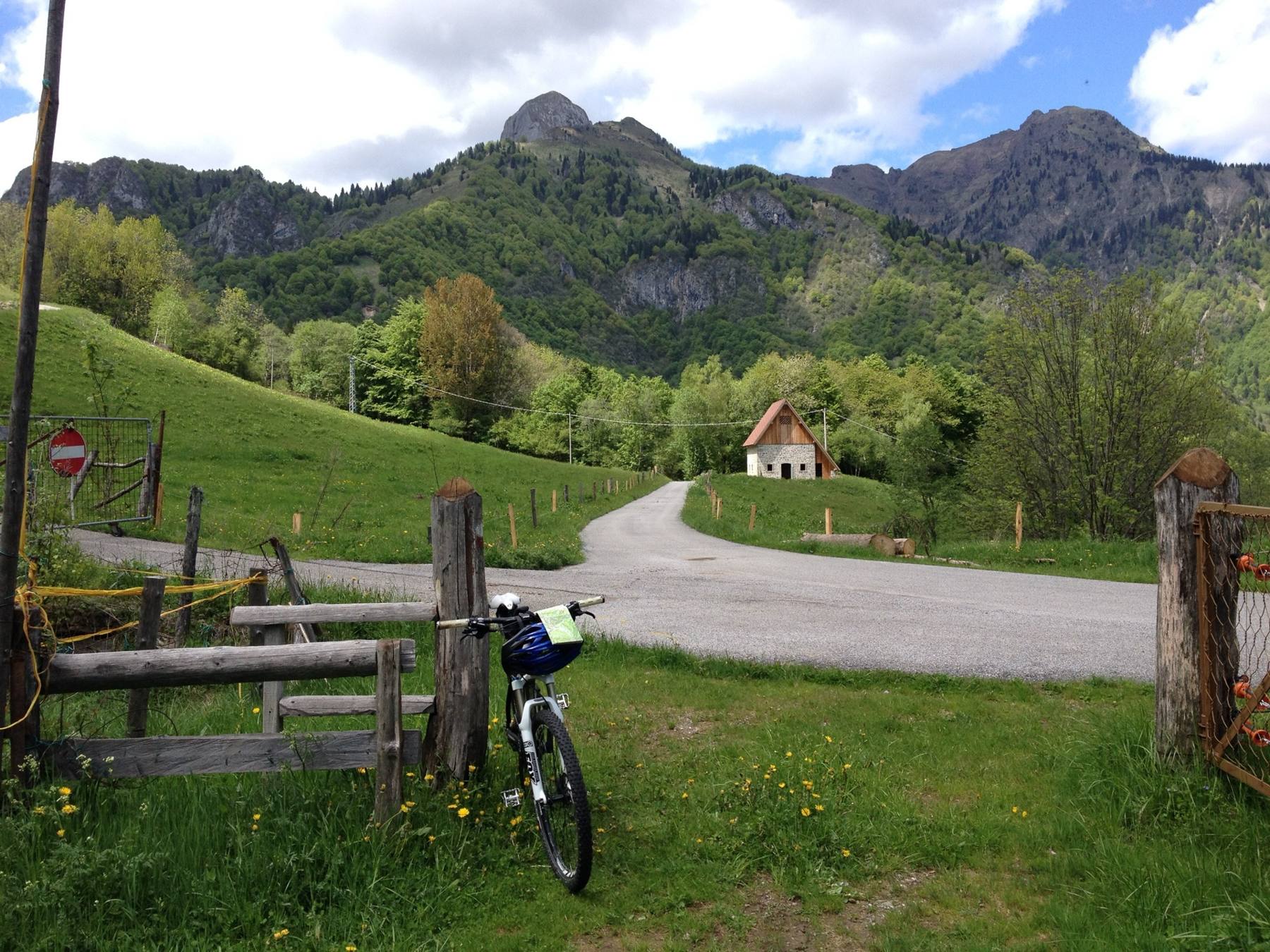 Ein Fahrrad am Holzzaun entlang einer Talstraße