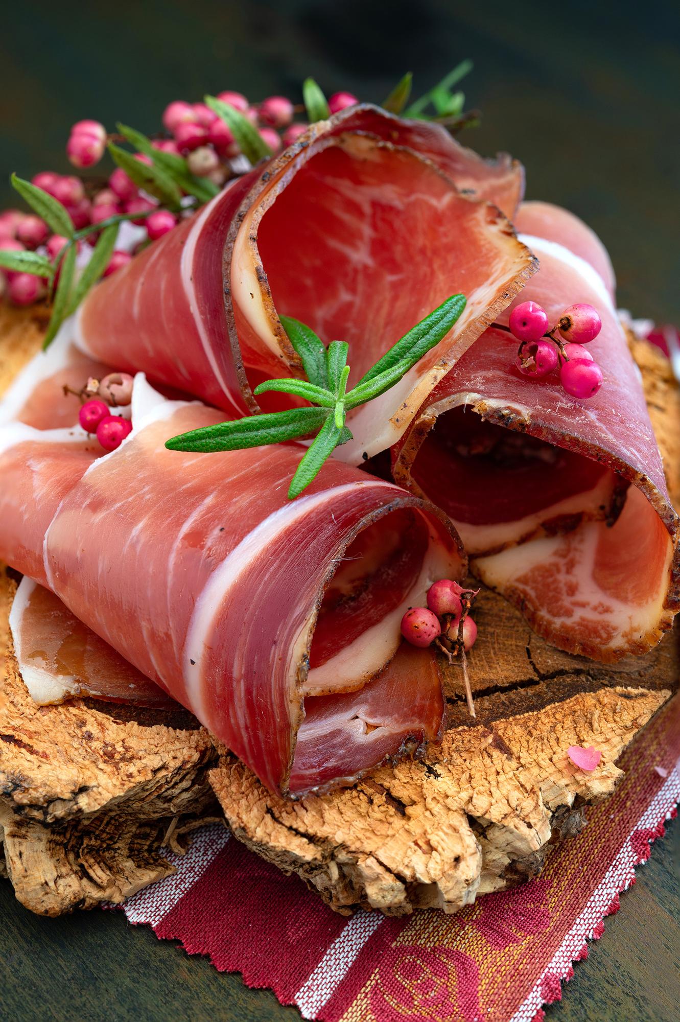 Speck and Carnic cured meats sliced on a board