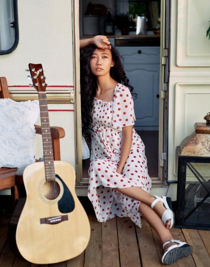 Una ragazza con la chitarra sulla porta del camper