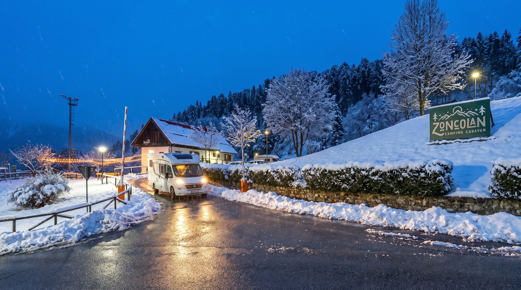 Een camper rijdt in de schemering door de slagboom van de camping, in de sneeuw
