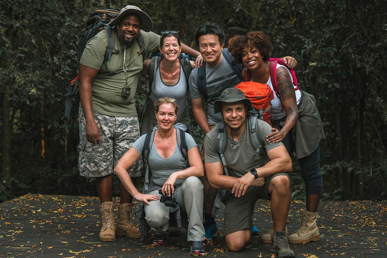 Een groep lachende wandelaars met rugzakken in het bos