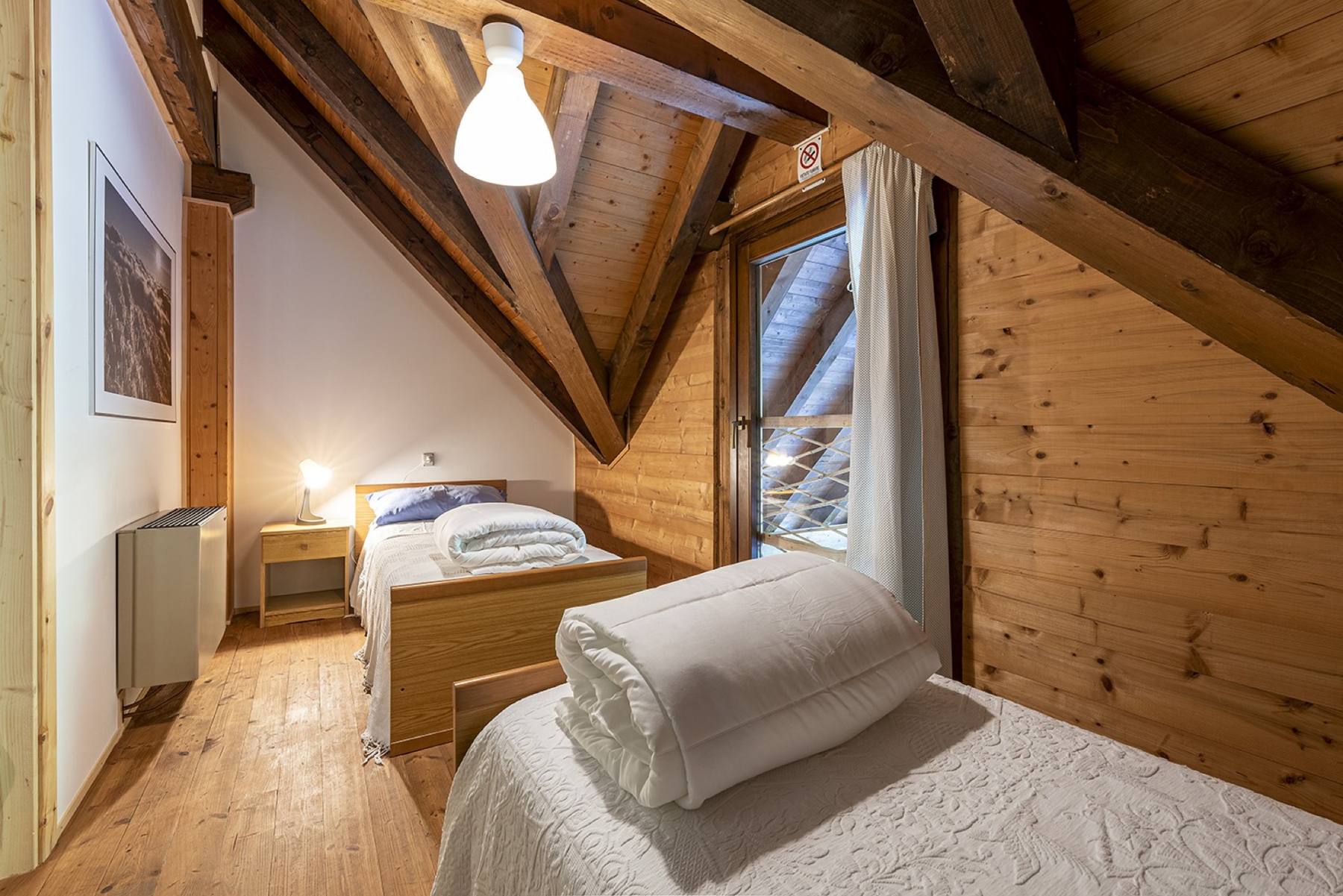 Camera dell'ostello con il letto e la finestra sul verde