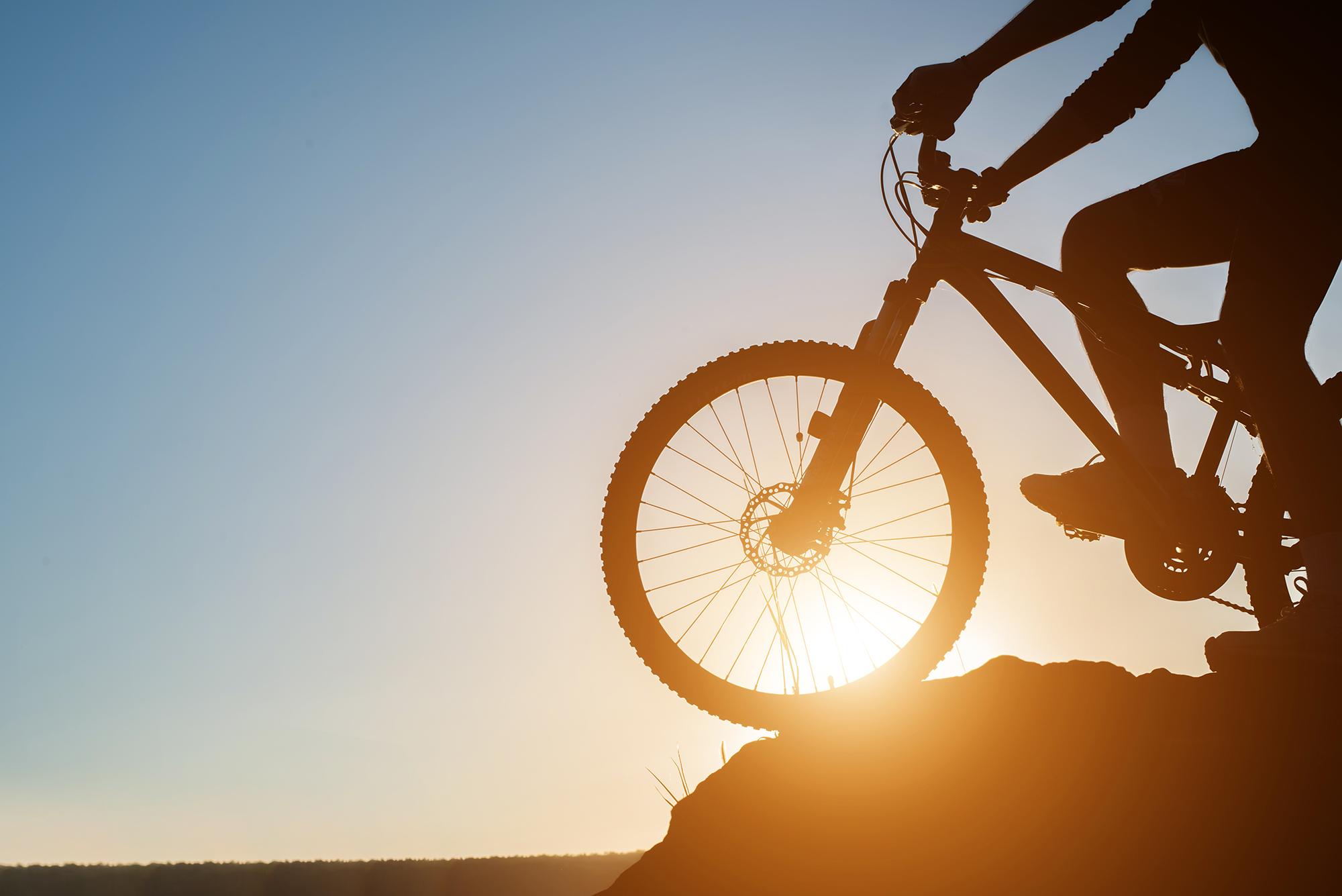 Ein Mountainbiker auf dem Grat im Gegenlicht bei Sonnenuntergang