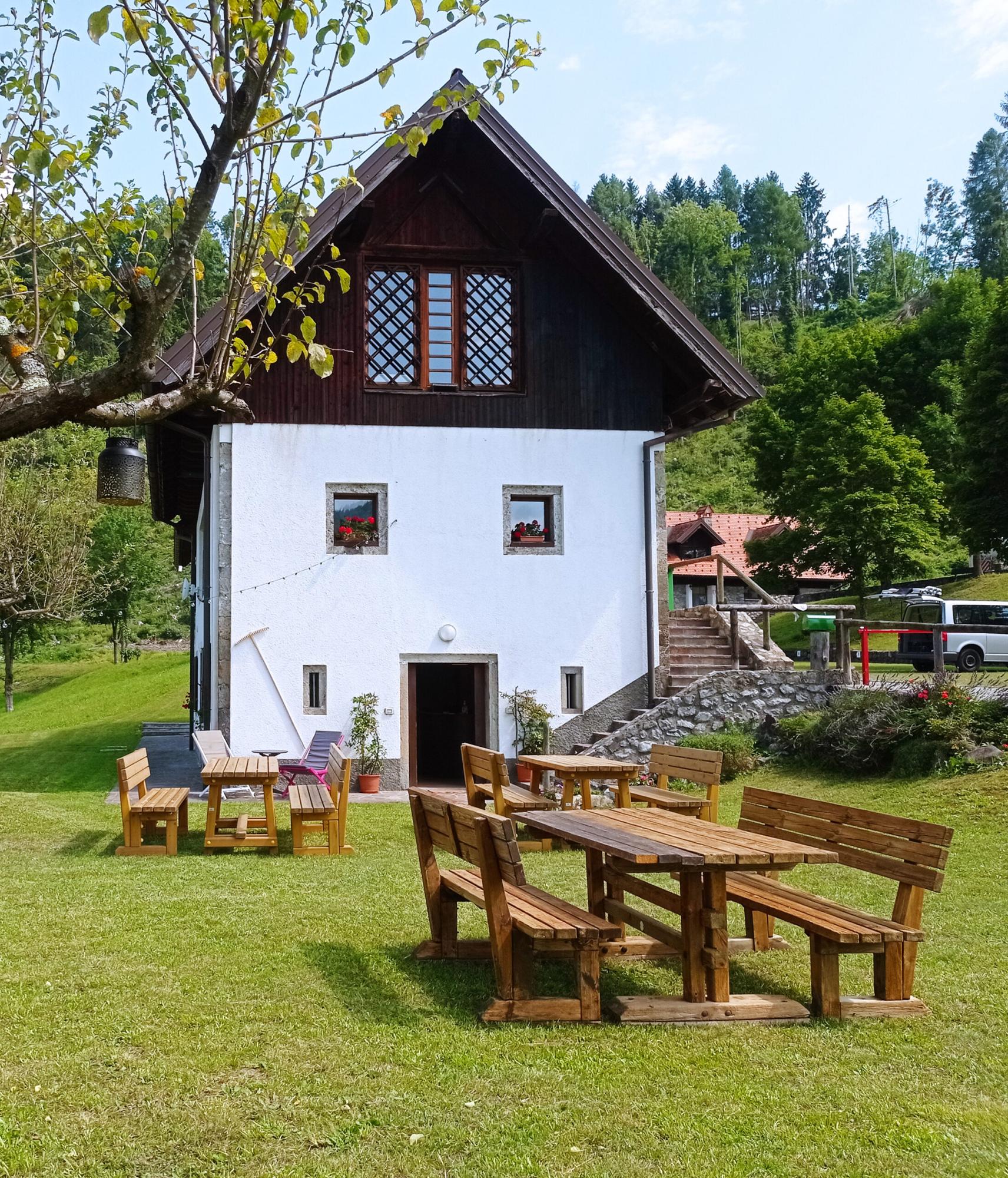 The Al Feralut restaurant building in summer, with wooden tables on the grass
