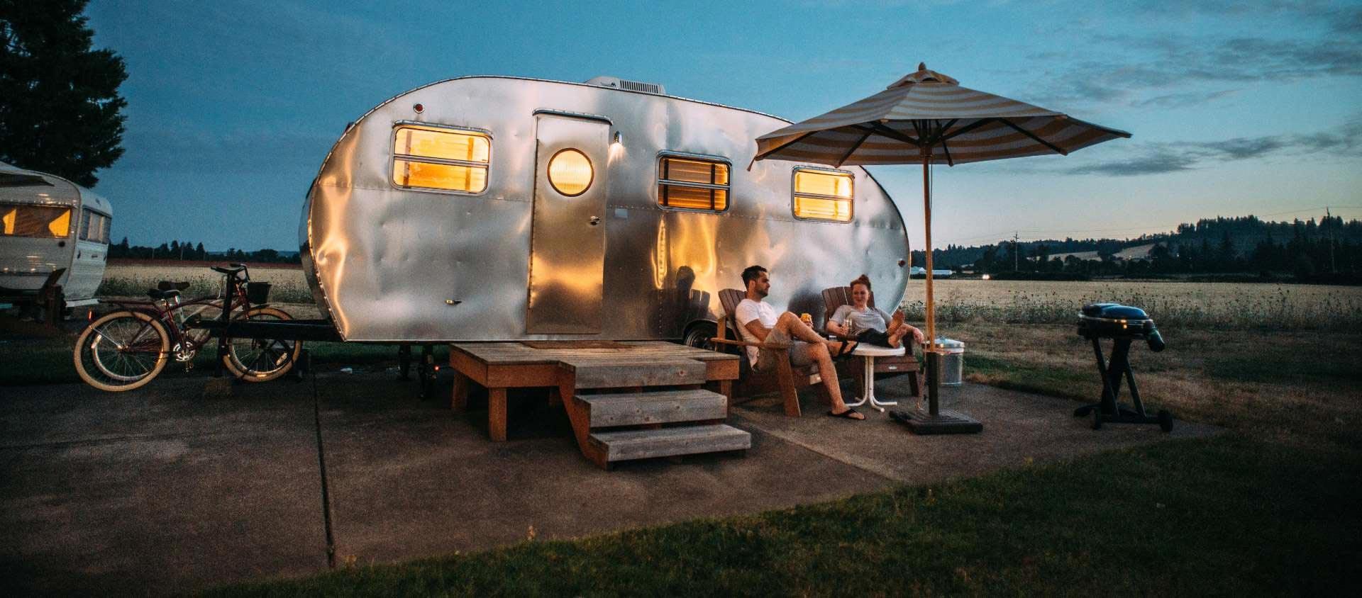Een caravan met de lichten aan bij zonsondergang, met de fietsen ernaast