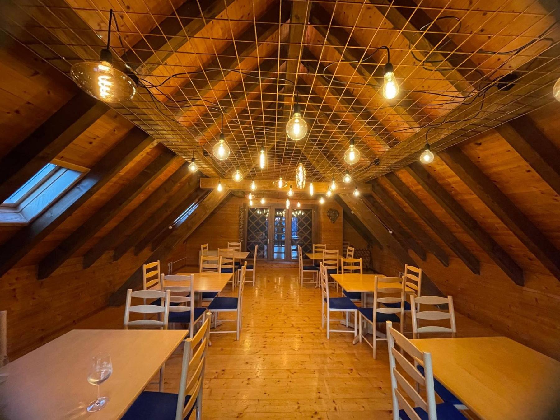 The attic dining room of the restaurant, with exposed beams and warm lights