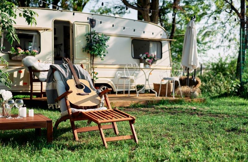 Een caravan op een staanplaats met ligstoelen op het gras