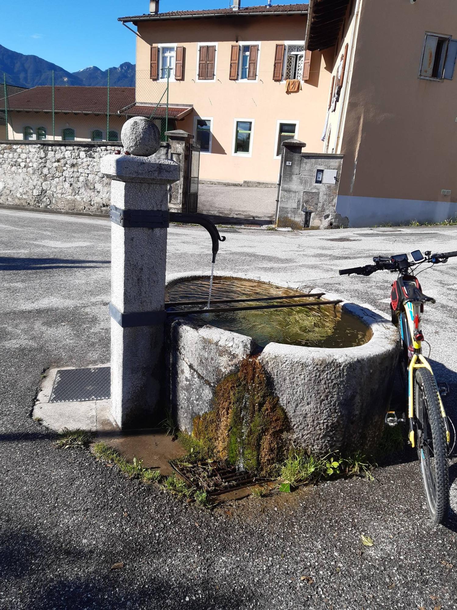 Ein steinerner Dorfbrunnen mit angelehntem Fahrrad