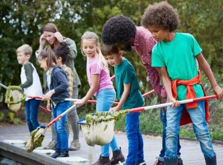 Kinder mit Keschern auf einer kleinen Holzbrücke