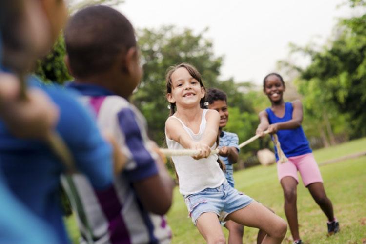 Kinder spielen Tauziehen auf der Wiese