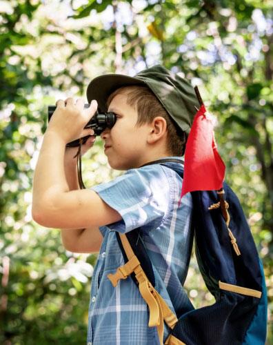 Ein Kind mit Fernglas und Rucksack