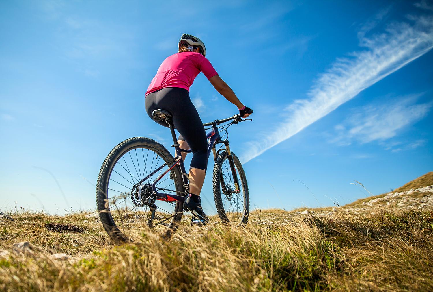 Een fietsster op een e-bike klimt over bergweiden