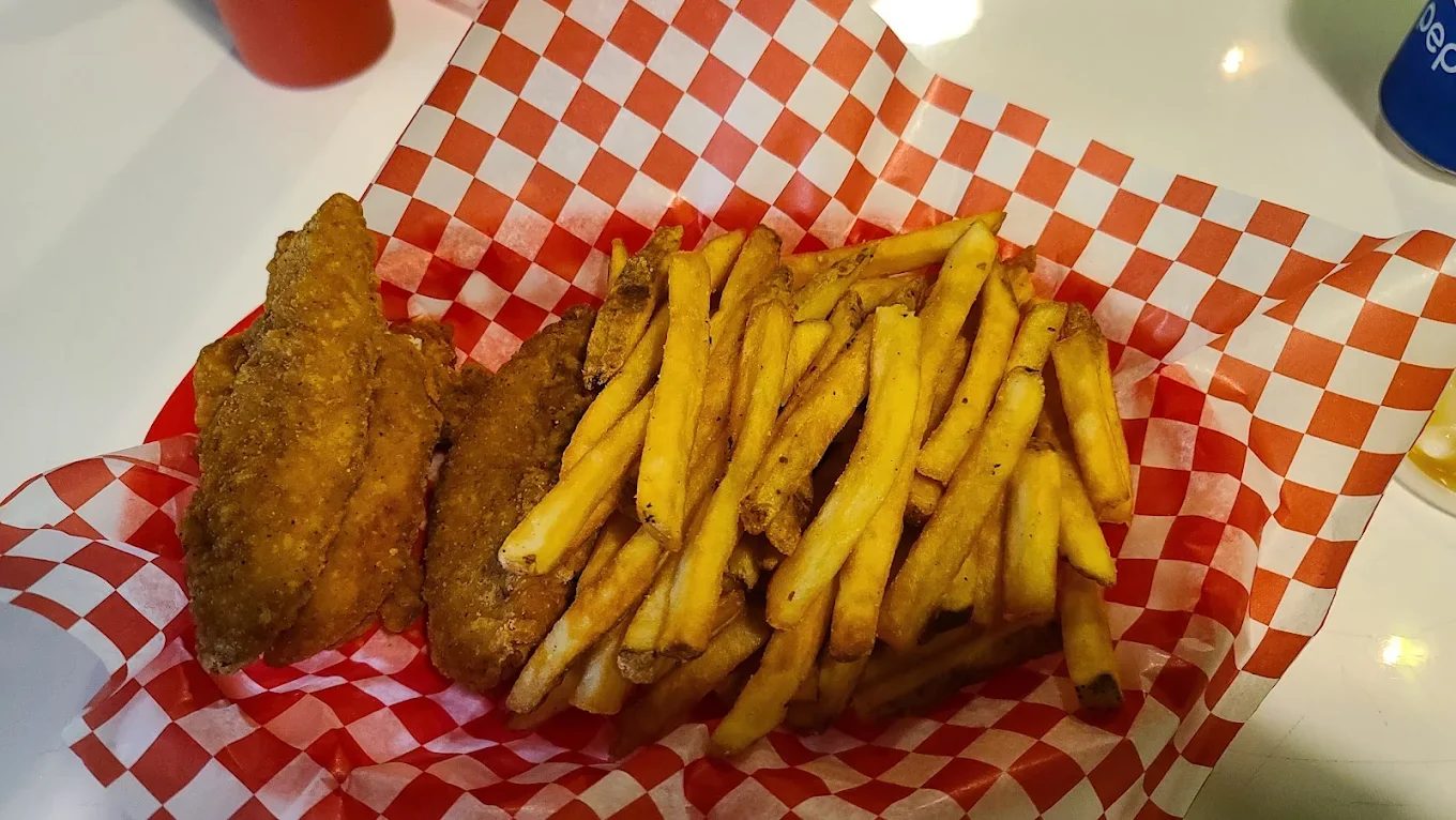 Crispy chicken fingers and golden fries served in a red-and-white checkered basket at The Harvest Table