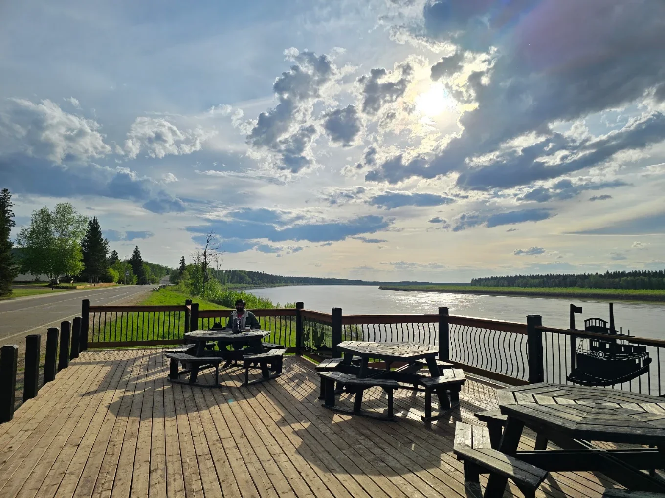 Wooden deck with picnic tables overhanging the bank of the Peace River, directly across from The Harvest Table