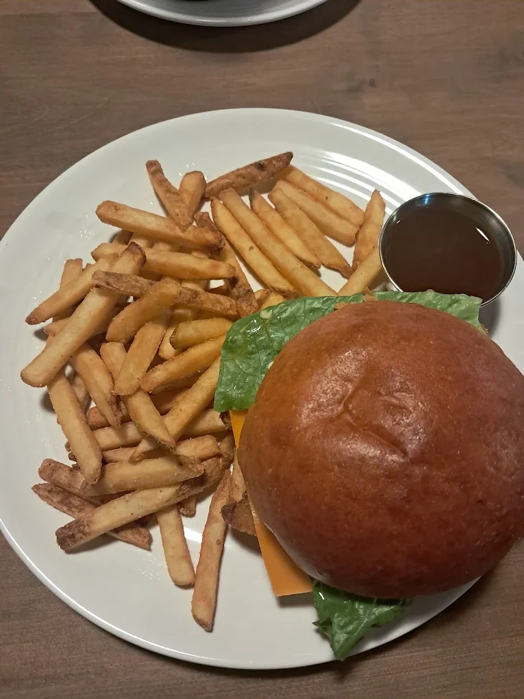 Crispy chicken burger with lettuce, tomato and golden fries on a white plate at The Harvest Table