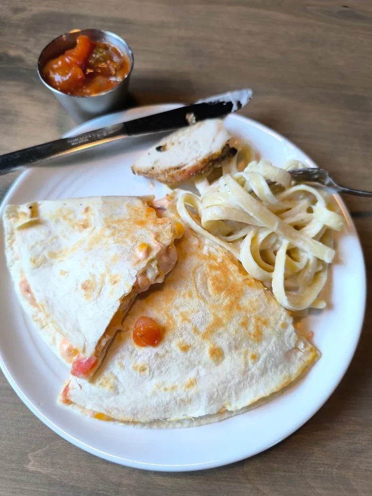Chicken quesadilla with salsa, grilled chicken and fettuccine on a white plate at The Harvest Table