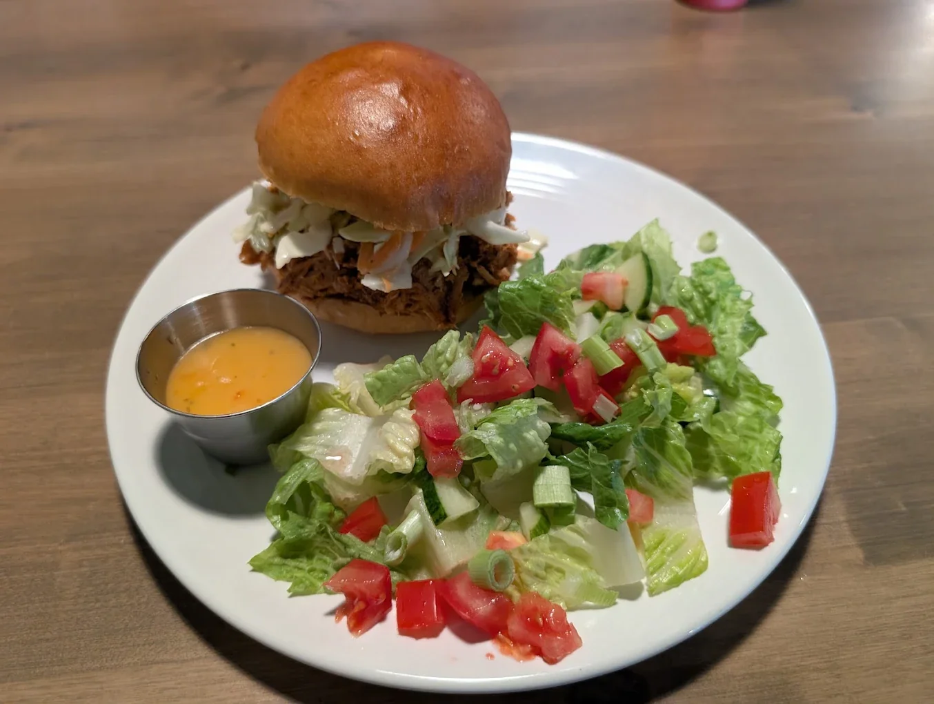 Pulled pork sandwich with fresh garden salad and dipping sauce served at The Harvest Table Fort Vermilion