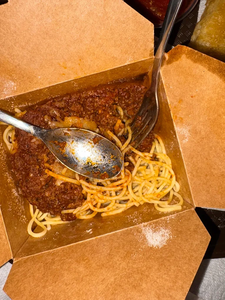 Chef's spaghetti with creamy tomato meat sauce in a takeout box, ready for a quick meal or take-home dinner
