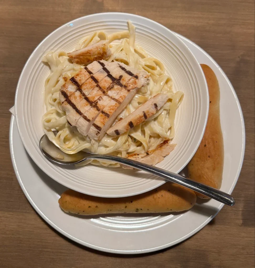 Chicken fettuccine Alfredo with grilled chicken breast and garlic breadsticks served at The Harvest Table in Fort Vermilion