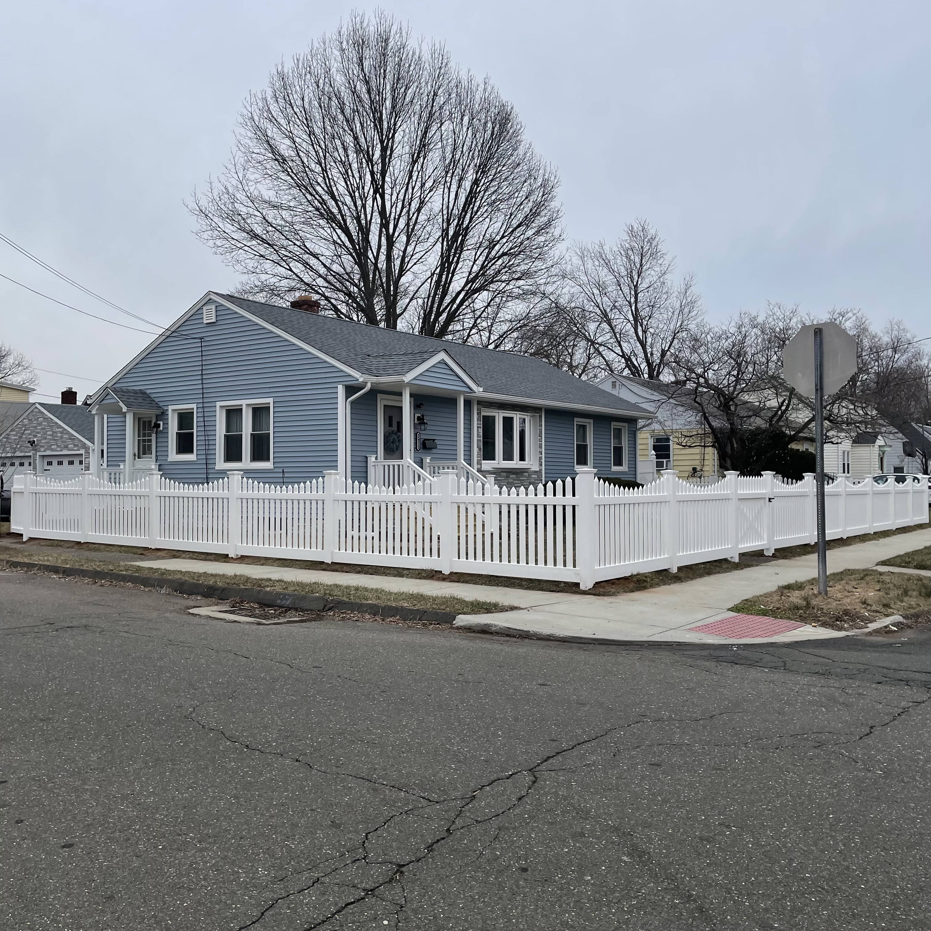 White fence in front of a blue house installed by New Haven Fence LLC