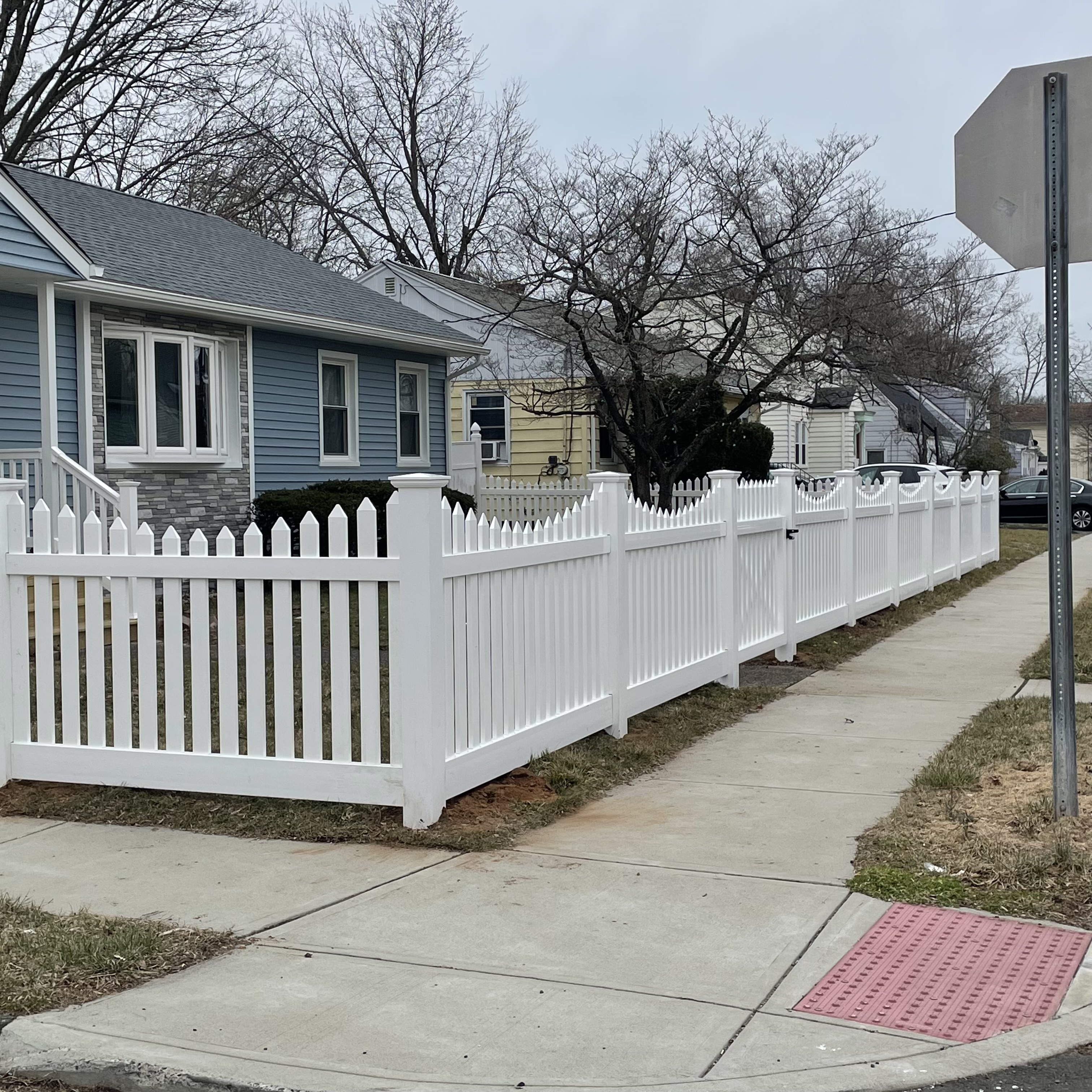 White fence installed in front of a blue house by New Haven Fence LLC